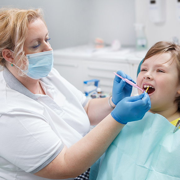 Child in dental chair having fluoride applied to their teeth