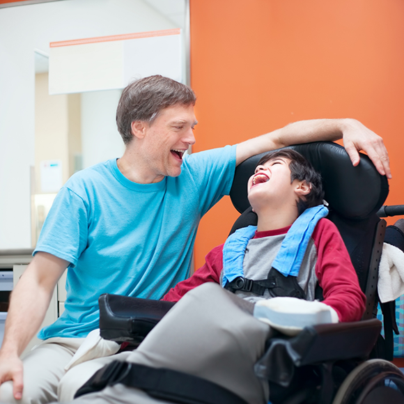 Dentist laughing with a young boy in a wheelchair