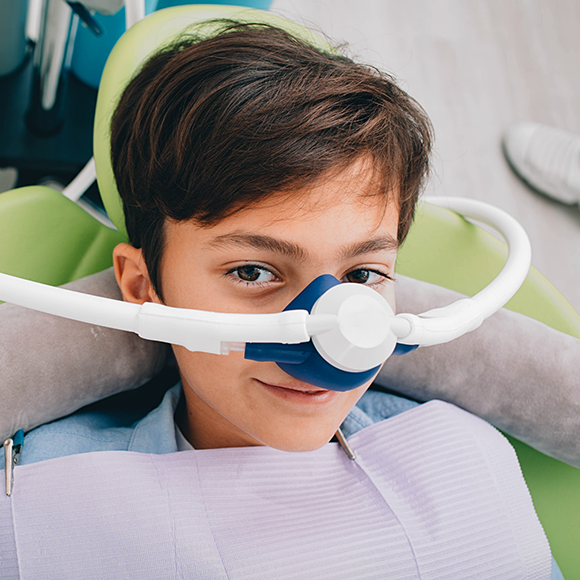 Young boy in dental chair with a nitrous oxide mask over his nose