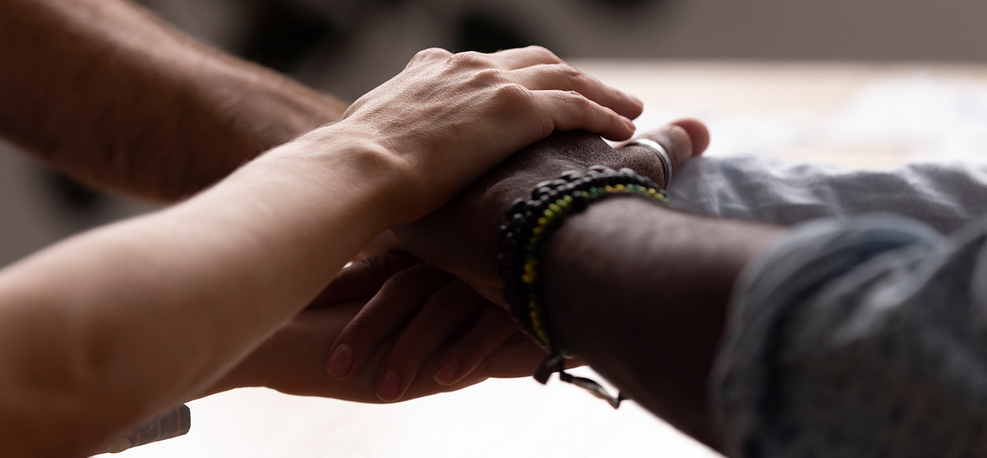 Two people placing their hands on top of each other