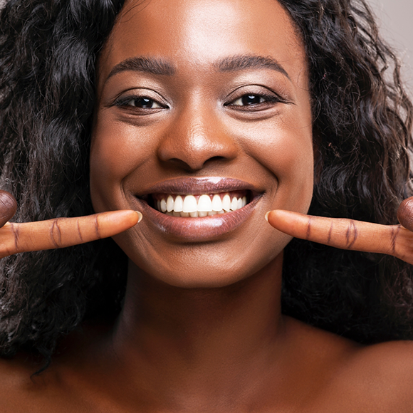 Young woman pointing to her smile