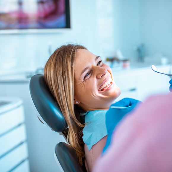 Woman in dental chair grinning at her dentist