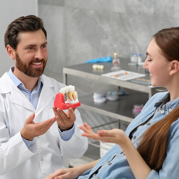 Dentist showing a model of a dental implant to a patient