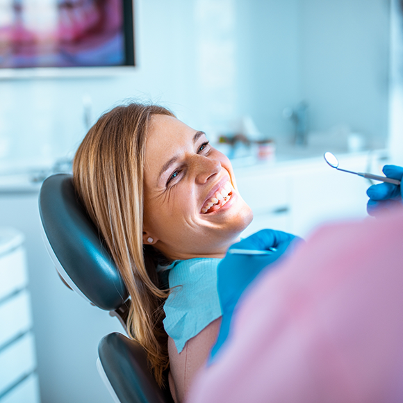 Woman in dental chair grinning at her dentist