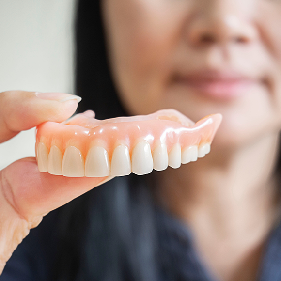 Dental professional holding a full upper denture