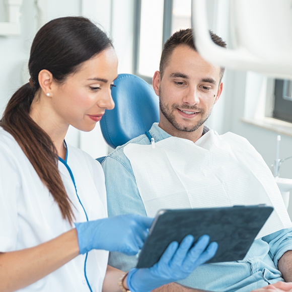 Dentist showing a tablet screen to a patient in the dental chair