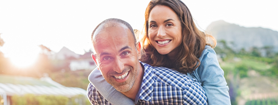 Smiling woman hugging a smiling man from behind