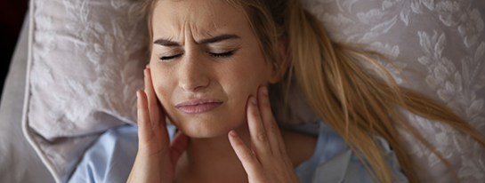 Woman holding the sides of her jaw in pain