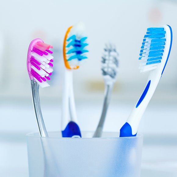 Four toothbrushes in a plastic cup