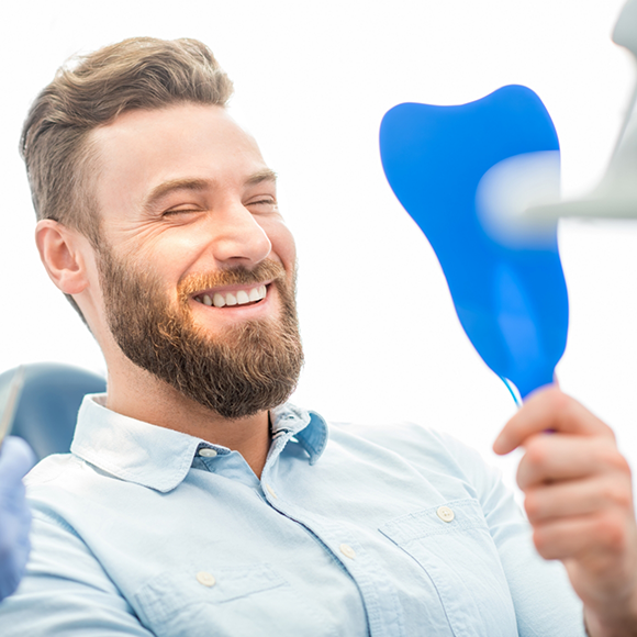 Bearded man looking at his smile in a mirror