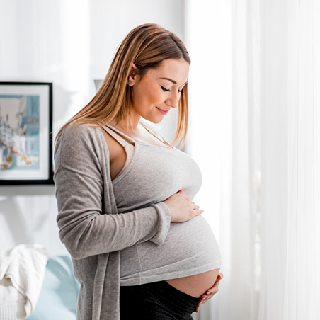 Pregnant woman smiling and holding her stomach