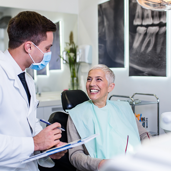 Senior woman in dental chair grinning at her dentist