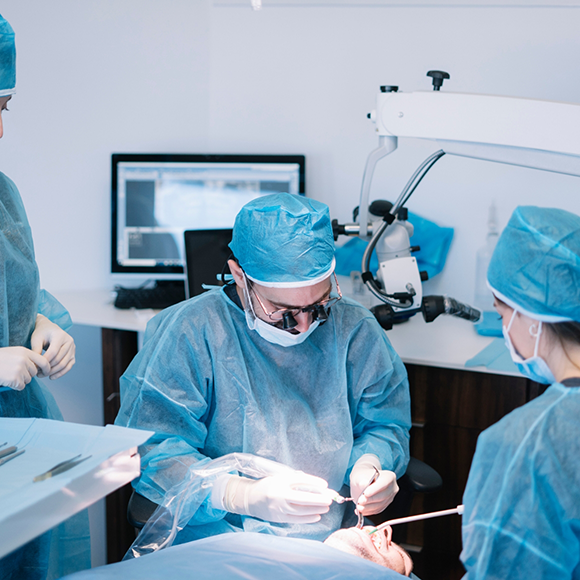 Dentist and assistants performing a wisdom tooth extraction on a patient