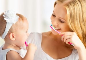 mother and baby brushing teeth together