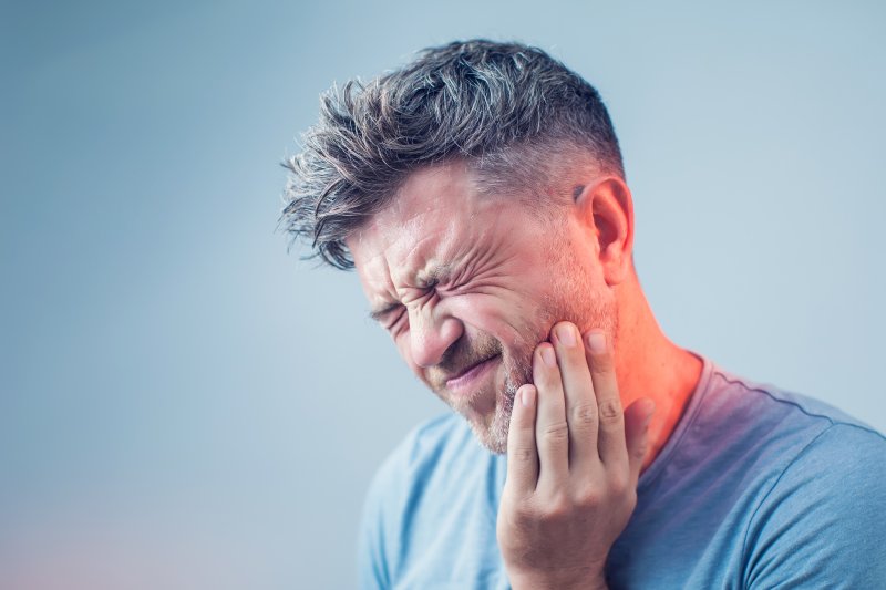 person with tooth pain holding cheek