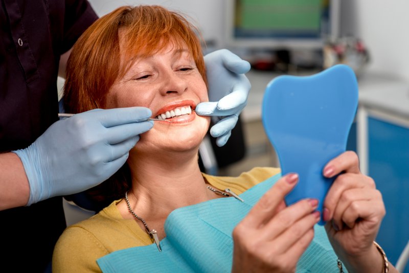 An older woman looking at her replacement dental veneers